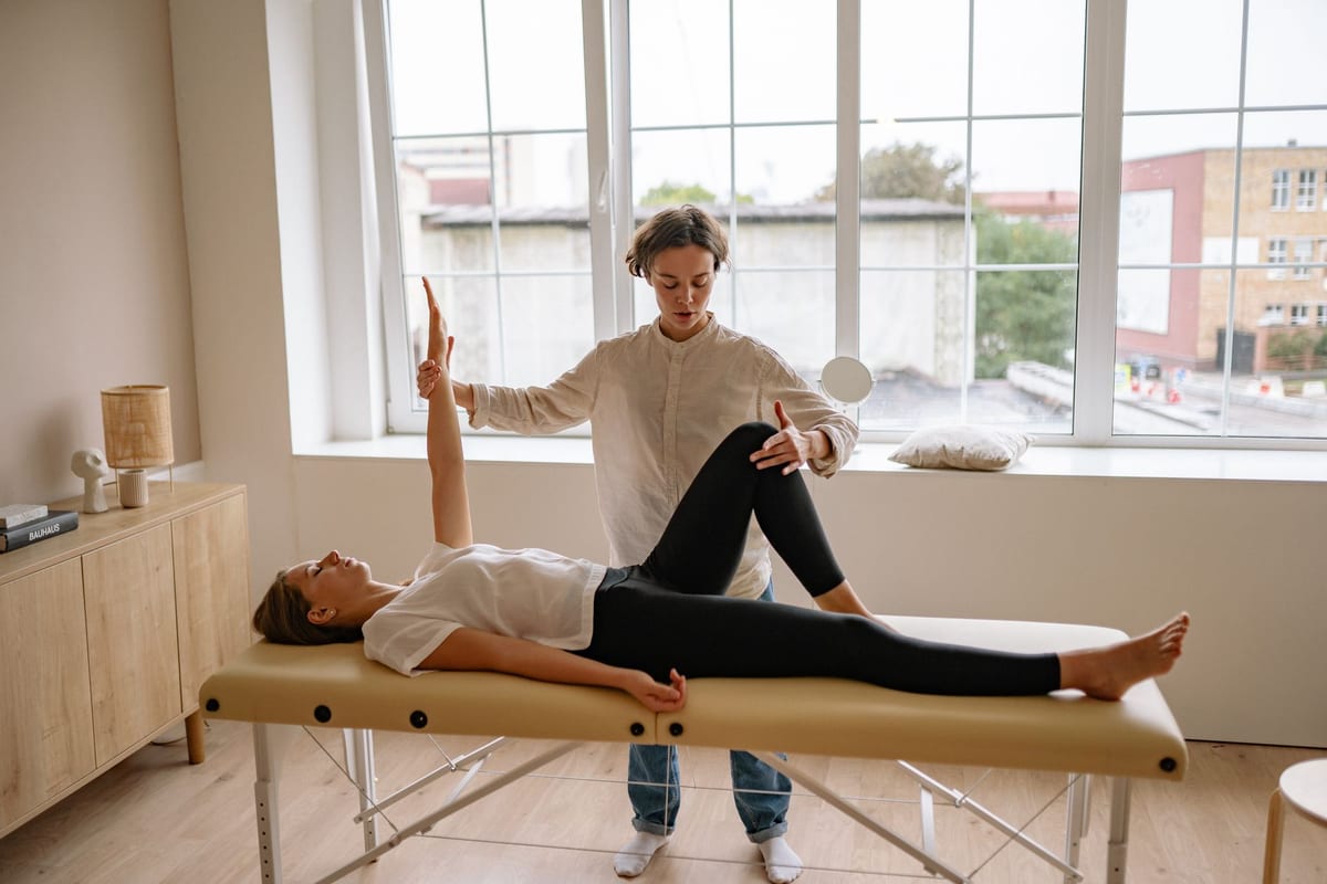 A therapist assessing a patient lying on a treatment table