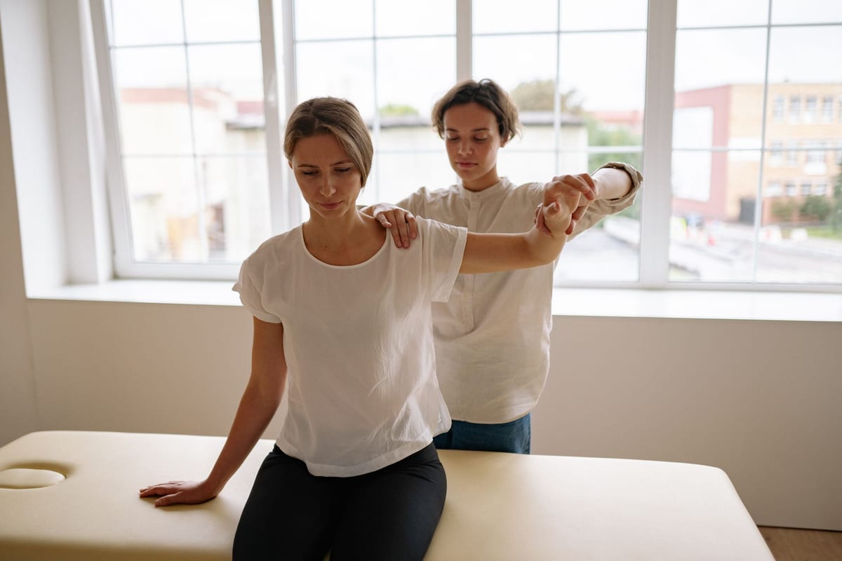 A therapist supporting a patient's raised arm through its range of motion